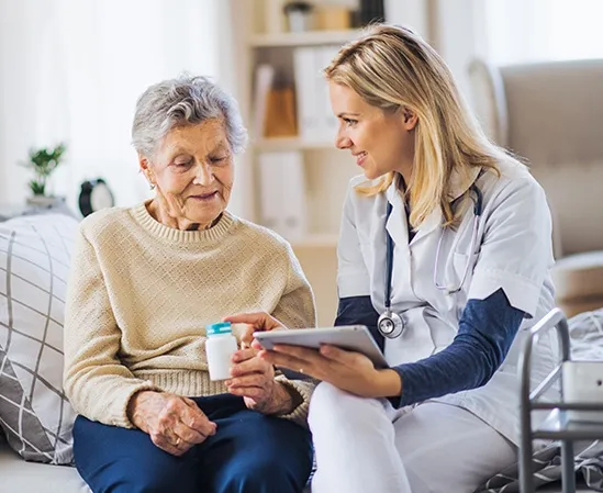 Caregiver explaining medication to an elderly woman in assisted living