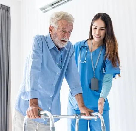 Professional caregiver helping a senior patient walk safely in assisted living