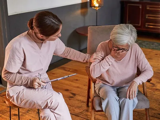 Caregiver comforting a senior woman with Alzheimer’s disease in an assisted living memory care facility