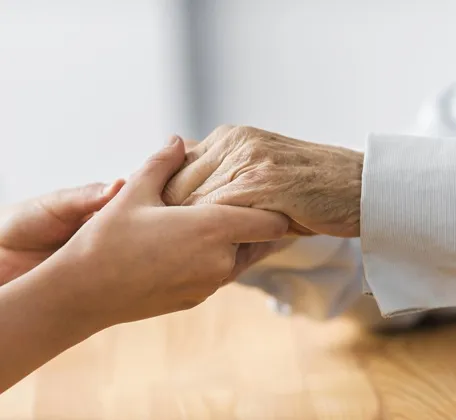 Caregiver holding the hand of a senior patient showing compassion and emotional support