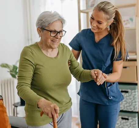 Caregiver supporting an older adult with walking assistance in a senior living home