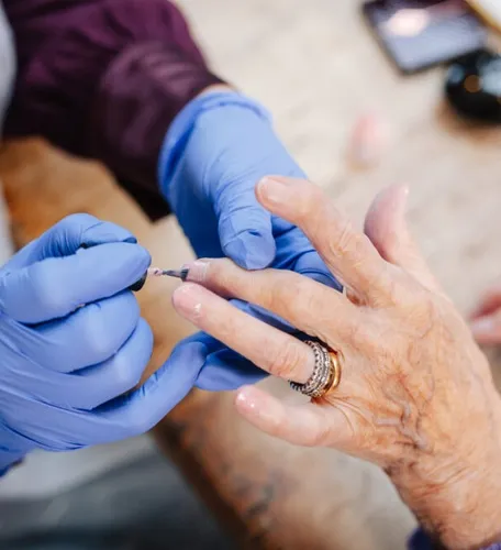 Caregiver providing nail care service to elderly woman during senior living personal care routine