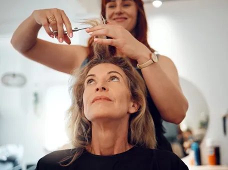 Senior woman getting a professional haircut from a hairstylist at a senior living community salon